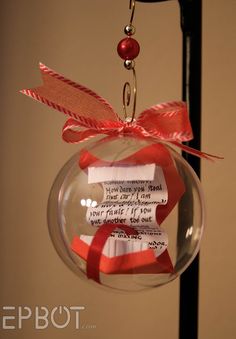 a glass ornament hanging from a metal pole with red ribbon and writing on it