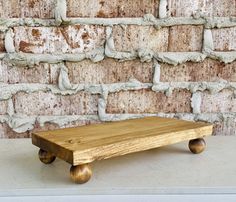 a wooden bench sitting in front of a brick wall with wheels on the bottom and sides