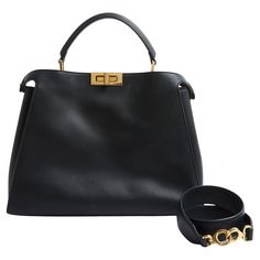 a black handbag next to a gold ring