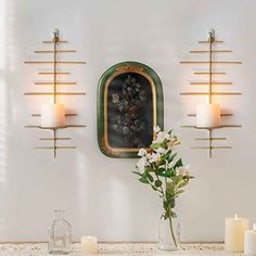 a vase filled with flowers sitting next to two candles on a table in front of a mirror