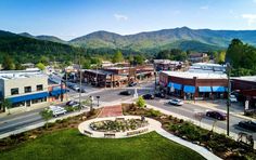 an aerial view of a small town with mountains in the backgrouund and cars parked on the street