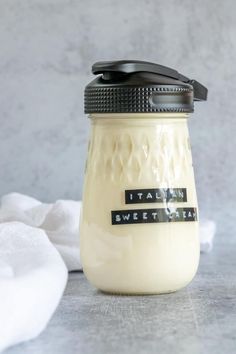 a glass jar with a black lid sitting on top of a table next to napkins