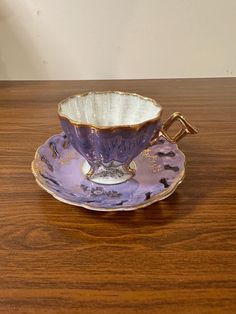 a purple cup and saucer sitting on top of a wooden table