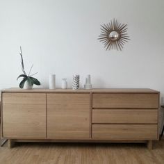 a wooden dresser with vases on top and a sun decoration above the drawers in front of it