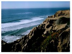 an ocean view with waves crashing on the rocks