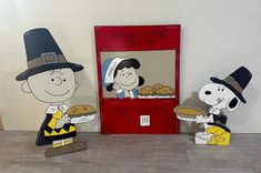 two paper cutouts of charlie brown and his thanksgiving pie stand in front of a red box