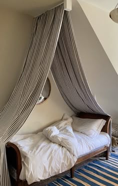 a bed with a canopy over it sitting in a room next to a wall and ceiling