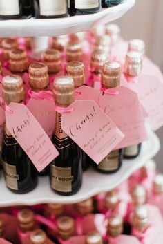 there are many bottles of wine on the shelves with pink ribbons and tags attached to them