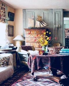 a living room filled with furniture and a table covered in a colorful cloth next to a fire place