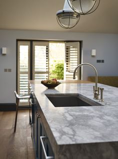 a kitchen with an island, sink and large window in the backround area