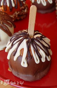 chocolate covered apples with white and brown icing on a red plate, ready to be eaten