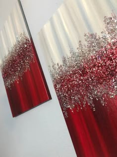 two red and white paintings with silver glitters on the bottom one is hanging on a wall