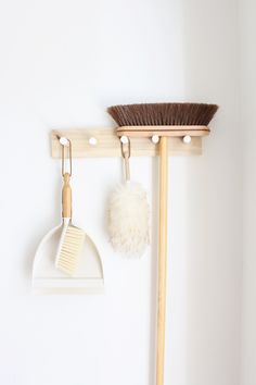 a broom, brush and dustpan hanging on a wall