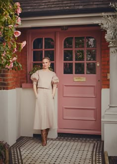 a woman standing in front of a pink door