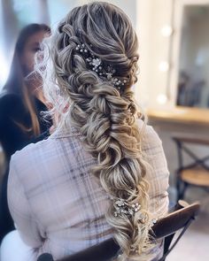 a woman sitting in a chair with her hair styled into a half - updo