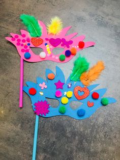 two carnival masks on the ground with colored pom poms