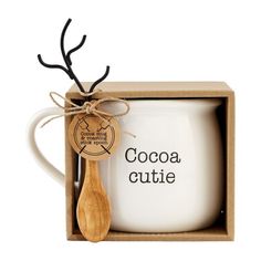 a white coffee mug with a wooden spoon in it and the words cocoa cutie printed on its side