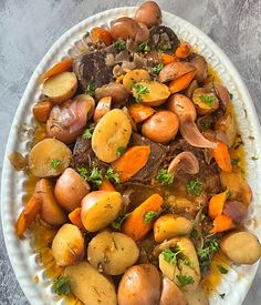 a white plate topped with potatoes and carrots on top of a gray tablecloth