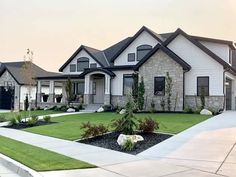 a large house with lots of windows and grass in front of the driveway, landscaping on both sides