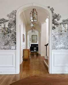 the hallway is decorated with wallpaper and wood flooring, along with an ornate chandelier