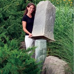 a woman standing next to a large rock