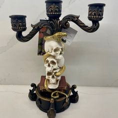 a candle holder with a skull on it and two candles in the middle, sitting on top of a table