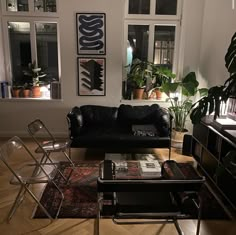 a living room filled with furniture and lots of plants on the windows sills