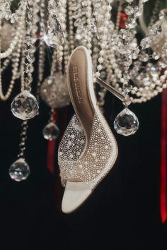 a pair of white high heels hanging from a chandelier with crystal beads on it