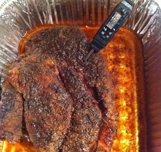 there is a piece of meat in the foil pan with a remote control on it