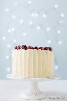 a cake with white frosting and raspberries sitting on top of a table