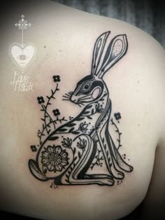 a rabbit tattoo on the back of a woman's shoulder