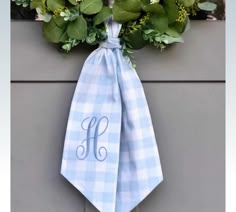 a blue and white checkered tie hanging on the side of a building with greenery