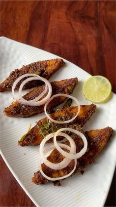 three pieces of fish with onions on a white plate