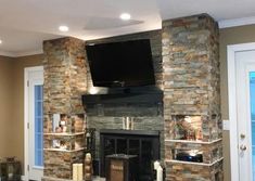 a living room with a stone fireplace and flat screen tv mounted on the wall above it