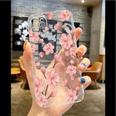 a woman holding up her phone case with pink flowers on it