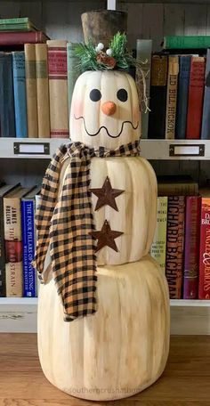 a snowman made out of wood sitting on top of a wooden floor next to bookshelves