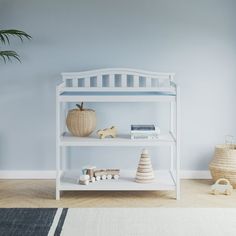 a white shelf with books and toys on it in a room next to a potted plant