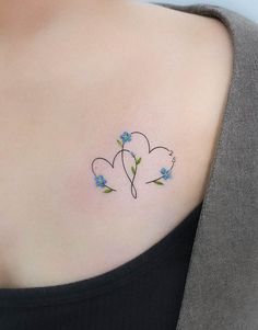 a woman's chest with two blue flowers on the left side of her neck