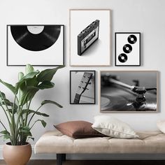 a living room filled with furniture and pictures hanging on the wall above a couch next to a potted plant