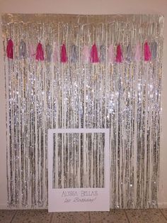 the curtain is decorated with pink and silver tassels for a special event or celebration