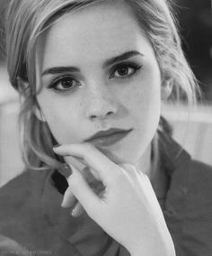 a black and white photo of a woman with her hand on her chin looking at the camera