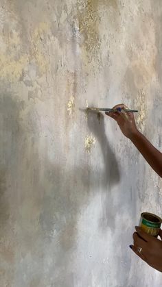 a woman is painting a wall with white paint and holding a brush in her hand