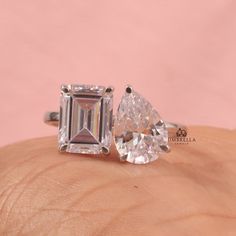 an engagement ring with two pear shaped diamonds on the side and a diamond in the middle