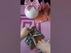 someone is cutting fabric with scissors on a table next to some flowers and an egg