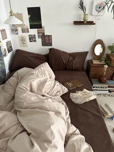 an unmade bed with brown sheets and pillows