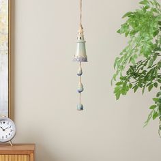 a clock hanging from the side of a wall next to a potted plant on a table