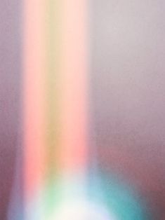 a blurry image of a vase with flowers in it and a rainbow light coming from the top