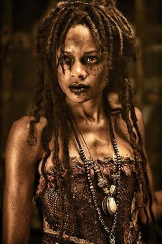 a woman with dreadlocks and makeup looks at the camera