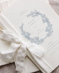 the wedding stationery is laid out on top of each other, with a ribbon tied around it