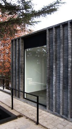 a building made out of concrete blocks and metal bars on the outside, with trees in the background